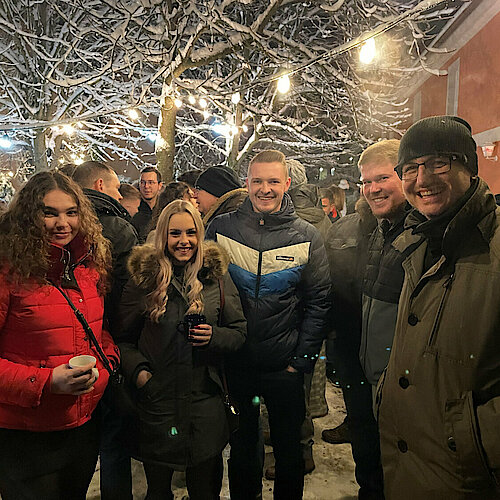 Kollegen lachen und stehen gemeinsam im verschneiten Garten